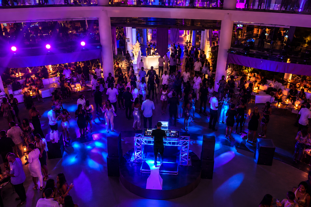Crowd dancing under purple stage lights at a resort night event